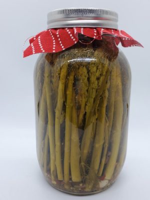 A jar of Jovial Java’s home-canned pickled asparagus with a red cloth lid